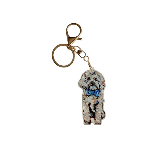 Cavapoo with blue bow acrylic dog bag charm and keychain featuring artwork by Chelsea McShane.